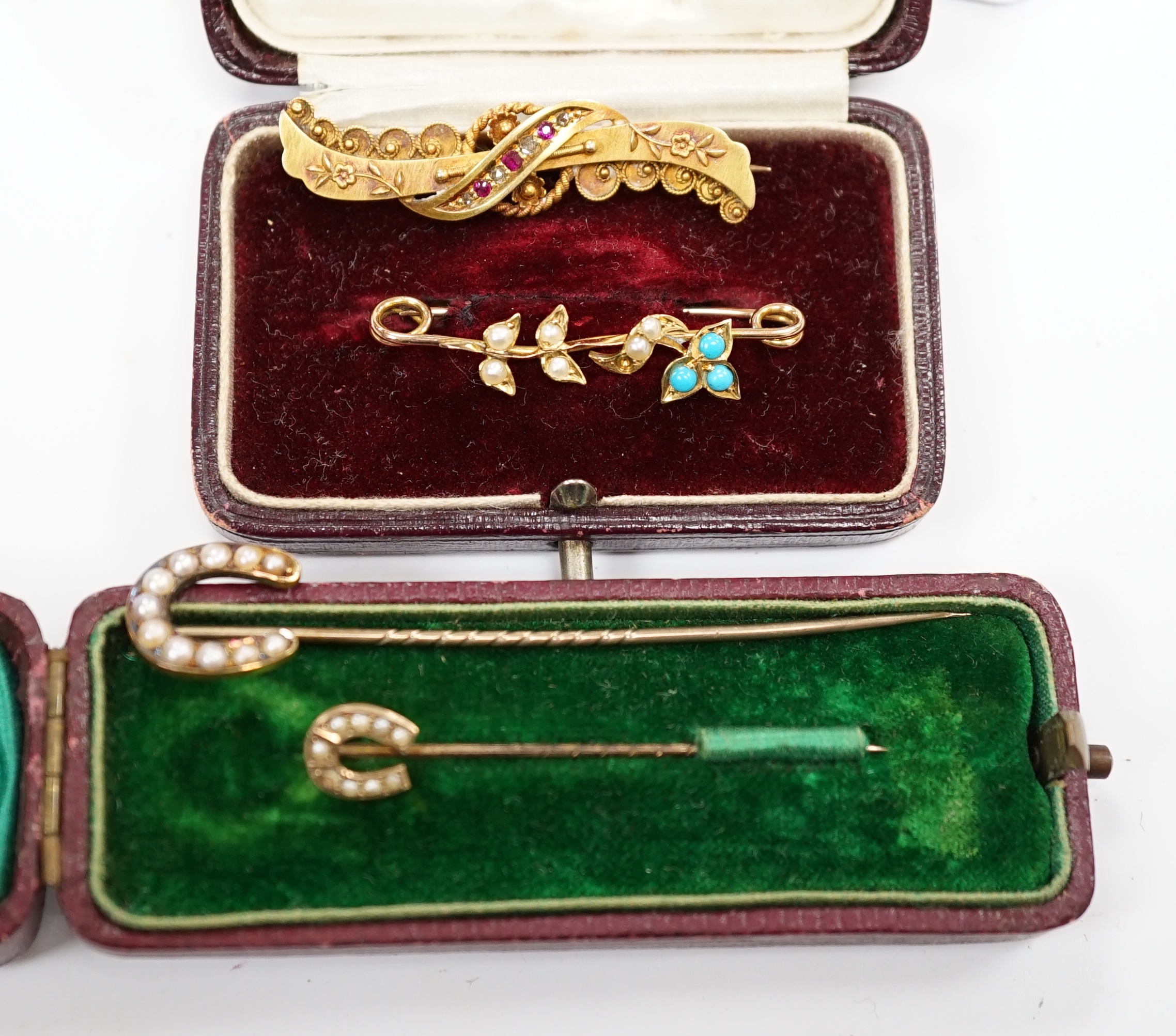A late Victorian 15ct gold, ruby and diamond chip set bar brooch, 39mm, a yellow metal, seed pearl and turquoise set bar brooch and two seed pearl set horseshoe stick pins, one stamped 9ct, the other 18. Condition - fair